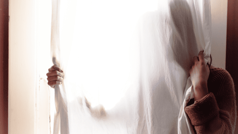 exit comfort zone, woman hiding behind curtains