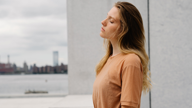 woman is pausing outside with her eyes closed