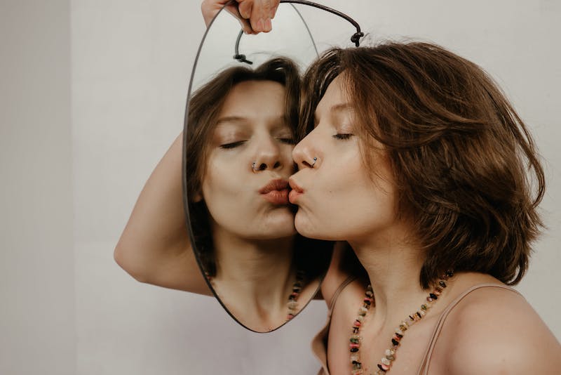 a girl is kissing the mirror