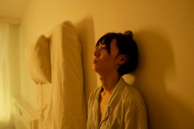 woman laying on the floor next to bed unable to fall asleep, she looks exhausted